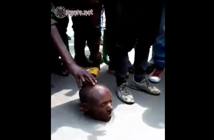A crowd with a severed man's head in the street